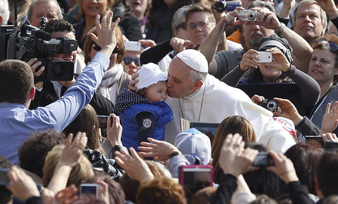 Pope kisses baby as he arrives to lead general audience at Vatican