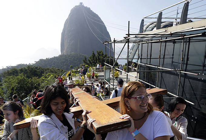 Catholics carry the World Youth Day cross as they prepare to celebrate Mass at Sugarloaf Mountain in Rio de Janeiro July 17. More than 320,000 registered pilgrims have begun arriving in Rio to take part in the main World Youth Day program with Pope Francis July 23-28. (CNS photo/Ricardo Moraes, Reuters)