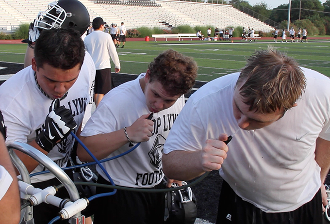 Bishop Lynch football players take a water break during practice at Roffino Stadium in Dallas. (Seth Gonzales/Texas Catholic)