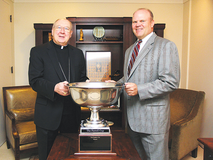 Bishop Kevin J. Farrell and Dave Klaudt,  a board member for the 2013 Bishop Farrell Invitational Golf tournament, display the Farrell Cup Challenge trophy, donated by Doug and Vicky Lattner, which will be awarded to the winning parish team during the Sept. 16 event at the TPC-Four Seasons Resort and Club and Cottonwood Valley in Irving. (Michael Gresham/Texas Catholic)