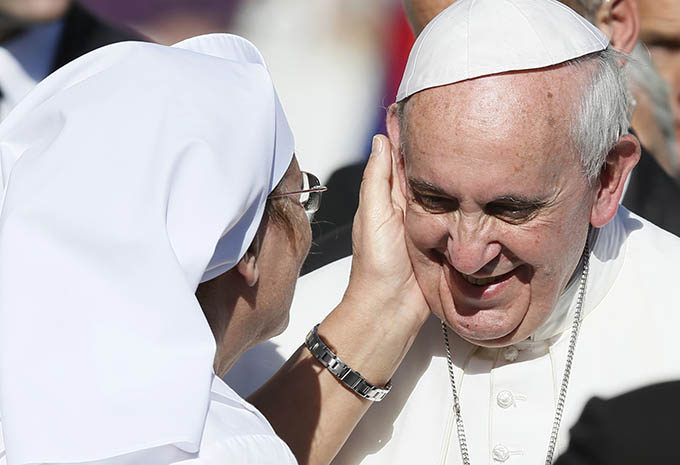 A caregiver accompanying a sick person greets Pope Francis during his general audience in St. Peter's Square at the Vatican Nov. 6. (CNS photo/Paul Haring)