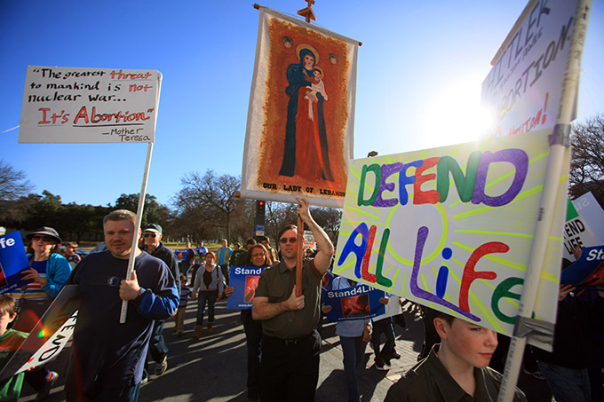 Tim O' Flaherty, of Lewisville, carries a banner of Our Lady of Lebanon as he walks with his family during the Stand4Life: Dallas March for Life, on Saturday, Jan. 18, 2014 in Downtown Dallas. (Ben Torres/Special Contributor)