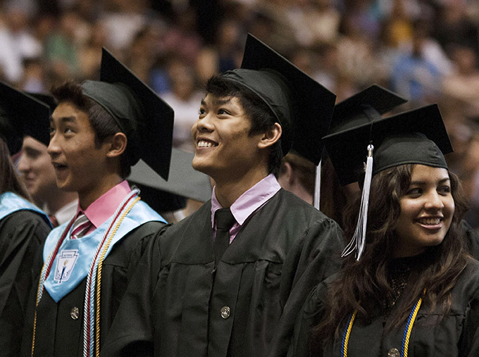 Derek Le, center, smiles as he watches his fellow classmates, on a jumbotron, take their seats at the beginning of the Bishop Lynch High School commencement ceremony May 18 at the Curtis Culwell Center in Garland. (JENNA TETER/The Texas Catholic)