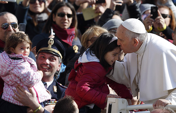 Pope Francis kisses a child as he arrives to lead his general audience in St. Peter's Square at the Vatican March 18. (CNS photo/Paul Haring)