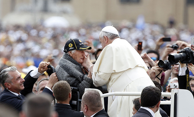 An elderly woman becomes emotional as Pope Francis greets her as he arrives for a weekly audience in St. Peter's Square at the Vatican.