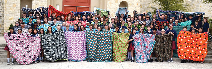 Seventh- and eighth-graders at Mary Immaculate Catholic School in Farmers Branch display hand-crafted blankets they will deliver to ill and traumatized children.