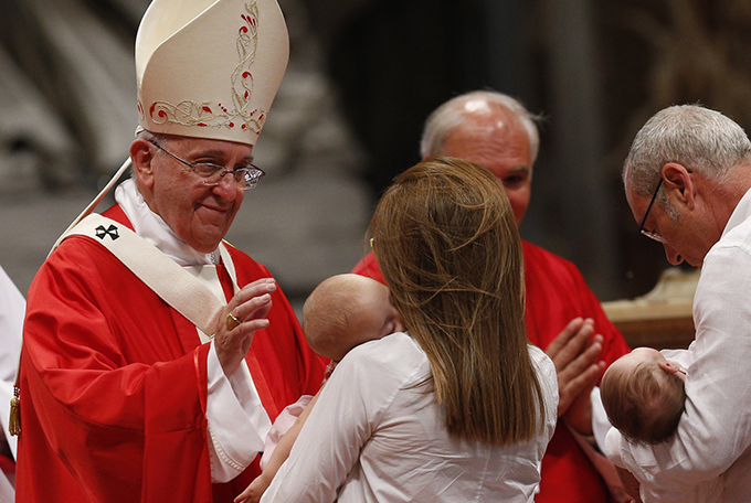 Pope Francis blesses babies as a couple present offertory gifts during the celebration of Mass marking the feast of Sts. Peter and Paul in St. Peter's Basilica at the Vatican June 29.  (CNS photo/Paul Haring)