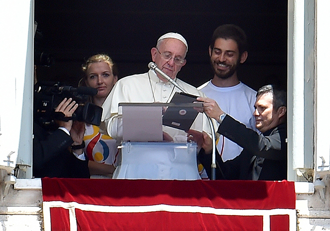 Pope Francis is flanked by two Polish youths as he uses a tablet to officially open online registration for World Youth Day 2016 in Poland. (CNS photo/Ettore Ferrari, EPA)
