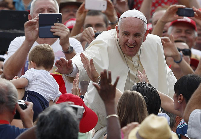 Pope Francis reaches to bless a baby during his general audience in St. Peter's Square at the Vatican. (CNS photo/Paul Haring)
