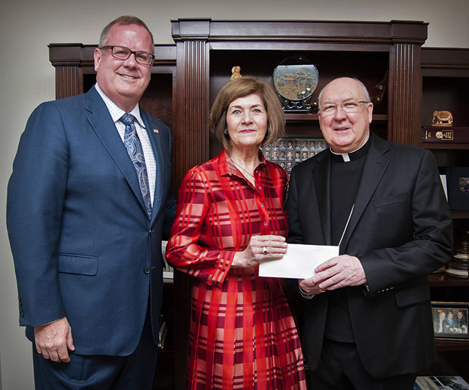 Matt Kramer, president and CEO of The Catholic Foundation, left, and Vicky P. Lattner, Board Chair of The Catholic Foundation, present a grant check to Bishop Kevin J. Farrell Jan. 8 at the Diocese of Dallas Pastoral Center.