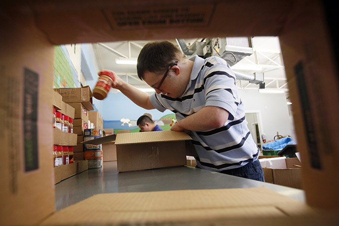 Notre Dame School of Dallas vocational student Chris Motes packs a jar of peanut butter while volunteering to make food packages at the San Felipe Food Distribution Center on March 2. The packages will be distributed to people in need as part of a food program created through a strategic partnership between Catholic Charities of Dallas and the Society of St. Vincent de Paul. (BEN TORRES/ Special Contributor)