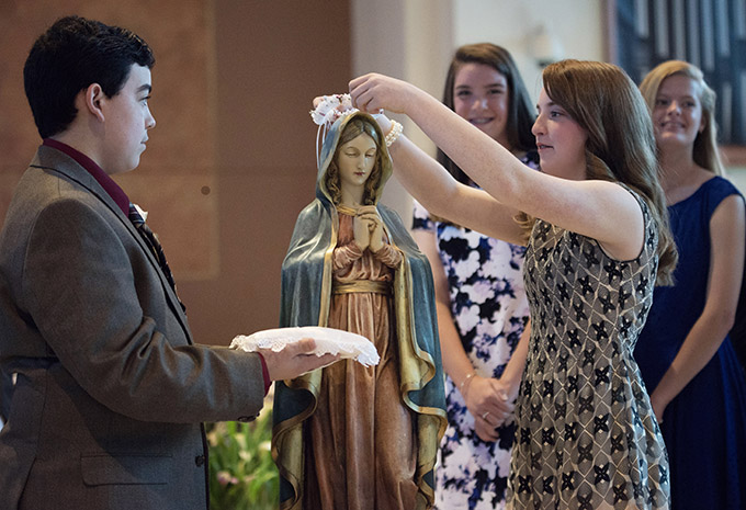 Kara McKemie crowns a statue of Mary while Xavier Garcia watches on May 5 at Mary Immaculate Catholic Church in Farmers Branch. (JENNA TETER/The Texas Catholic)