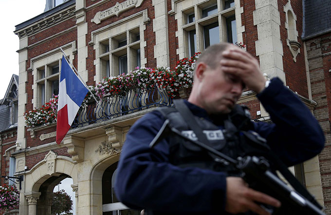 A policeman reacts as he secures a position in front of city hall after two assailants killed 84-year-old Father Jacques Hamel and took five people hostage during a weekday morning Mass at the church in Saint-Etienne-du-Rouvray, France, near Rouen July 26. (CNS photo/Pascal Rossignol/Reuters)