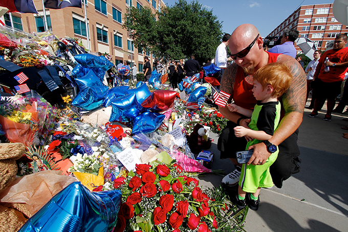 Jamie Cummings and his son T.J., 2, visit a memorial in front of the Dallas Police Department headquarters on July 11 in Dallas. Five police officers were killed on July 7 when a sniper opened fire during a protest in downtown Dallas. (KEVIN BARTRAM/Special Contributor)