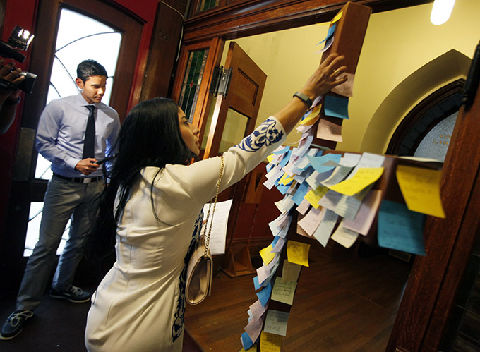 Parishioner Cassandra Hernandez leaves a message on a crucifix showing her support for the victims of the Black Lives Matter rally shooting, before the start of a Mass for Hope and Healing conducted by Dallas Bishop Kevin Farrell, on July 9 at the Cathedral Shrine of the Virgin of Guadalupe in Dallas. (Ben Torres/Special Contributor)