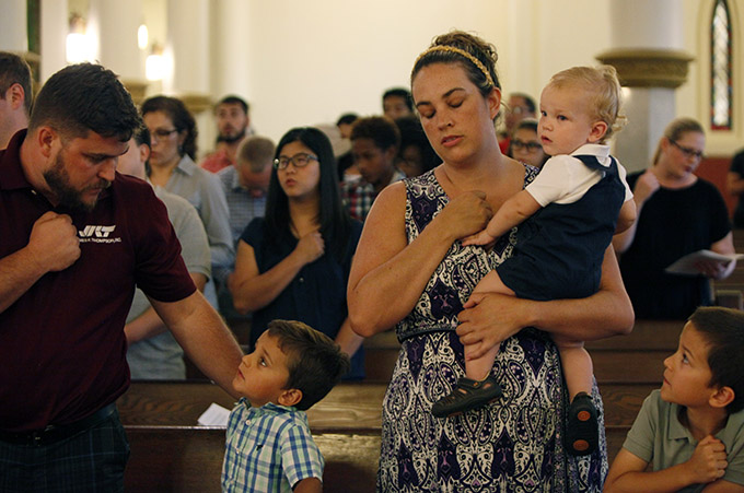 A woman and her family say a prayer at the start of Mass for Hope and Healing on July 9 at the Cathedral Shrine of the Virgin of Guadalupe in Dallas. (Ben Torres/Special Contributor)