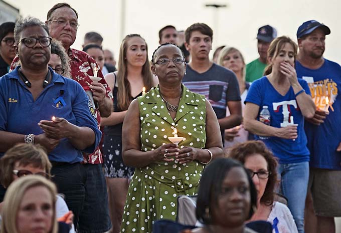 Patricia Kirkendoff of Corsicana, middle, takes part in the candlelight vigil for DART Police Officer Brent Thompson on July 10  in the parking lot at Corsicana High School. (JENNA TETER/The Texas Catholic)