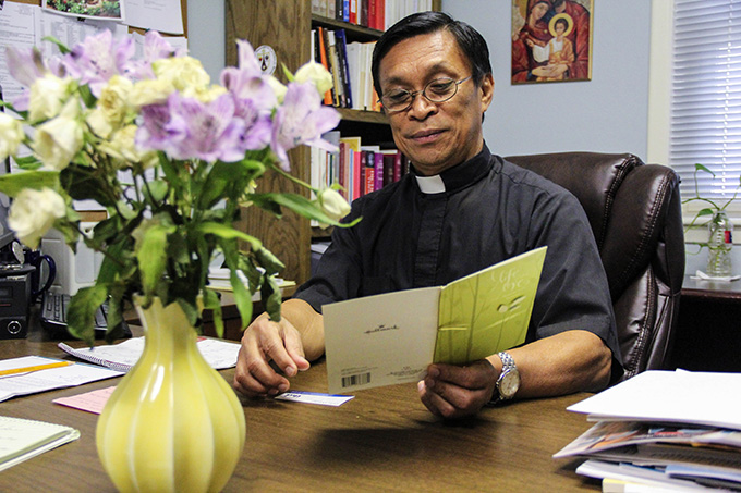 Father Albert Becher, pastor of Holy Family of Nazareth Catholic Church in Irving, reads over a card given to the parish from the Islamic Center and School of Irving.