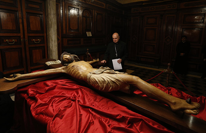 Cardinal Angelo Comastri, archpriest of St. Peter's Basilica, looks at a wooden crucifix from the 14th century during a media opportunity to showcase its restoration in St. Peter's Basilica at the Vatican Oct. 28. The crucifix is one of the few items that was present in the original St. Peter's Basilica. The restoration was funded by the Knights of Columbus. (CNS photo/Paul Haring)